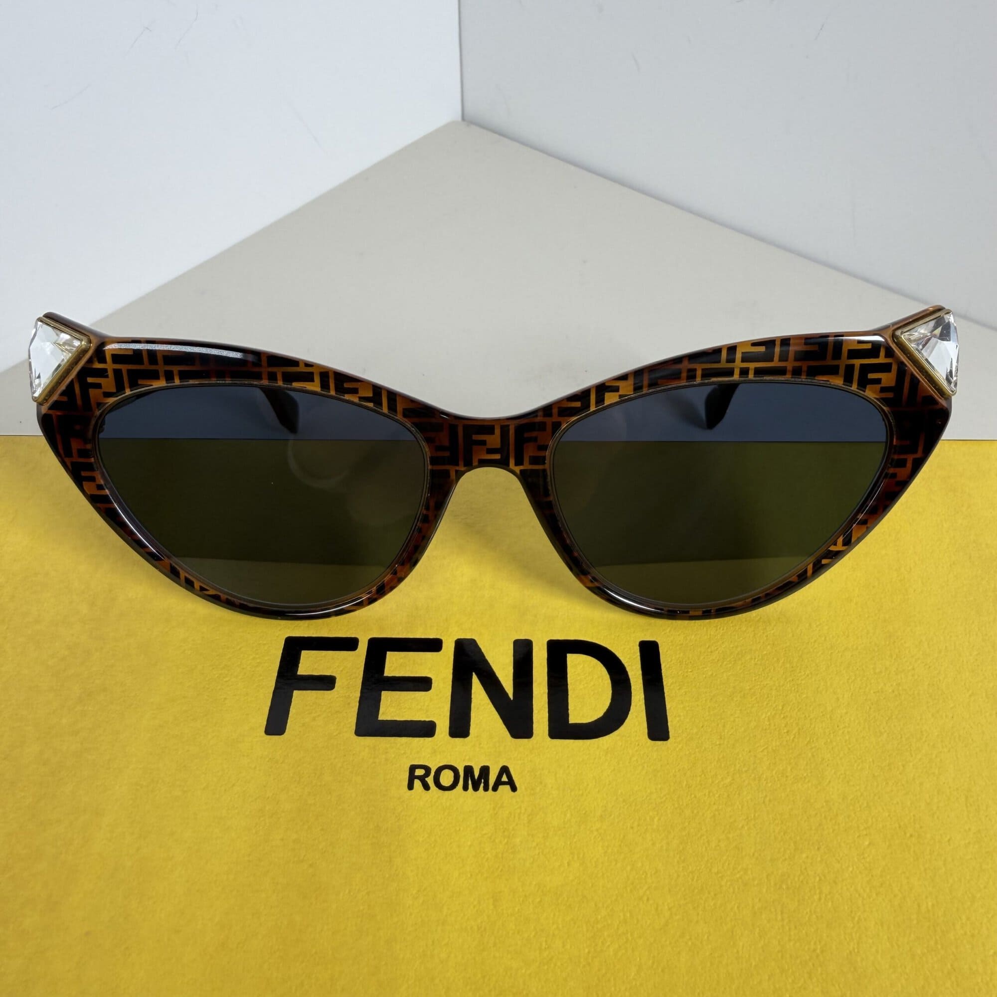 Front view of Fendi FF 0356/S monogram cat-eye sunglasses resting on branded yellow background