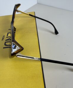 Side angle of Fendi sunglasses showing gold-tone temple arm with engraved logo and faceted corner stud