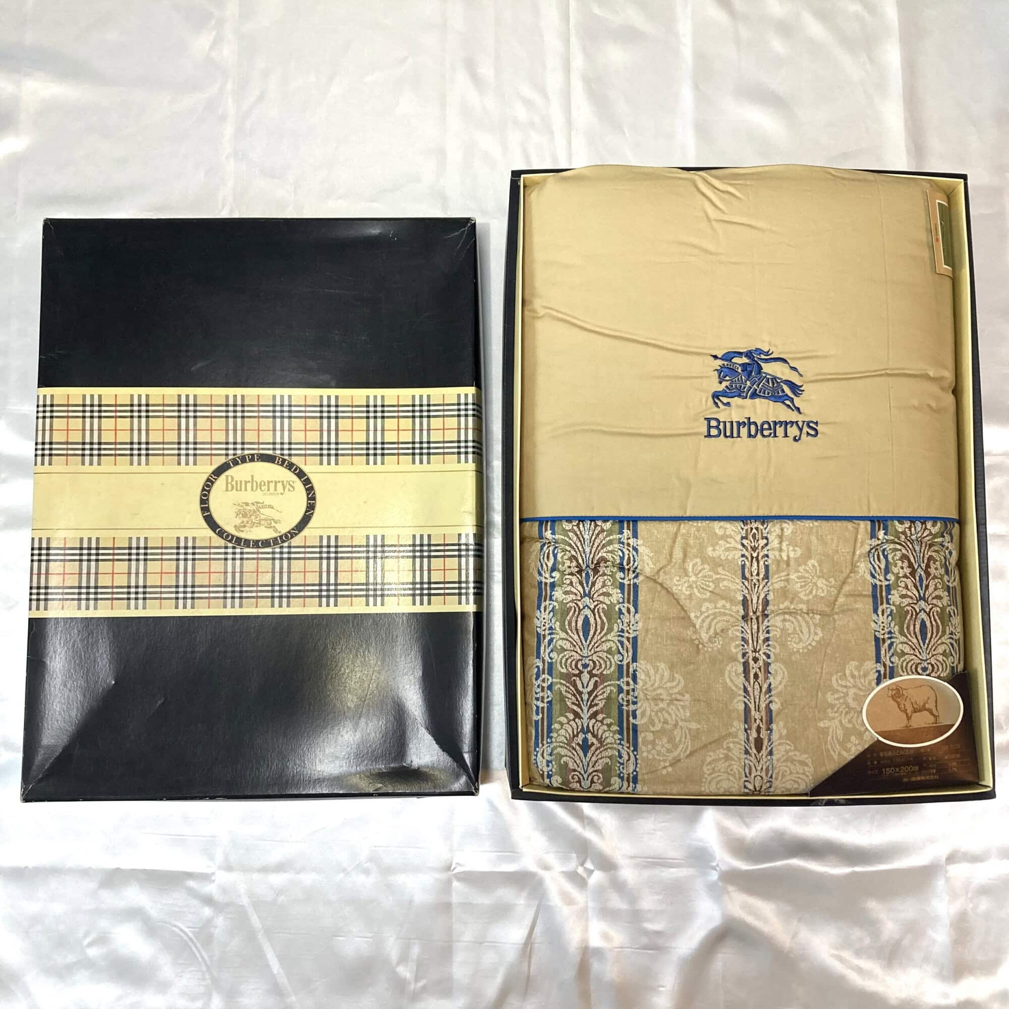 Burberrys damask quilted comforter folded inside its box next to the branded check-banded lid.