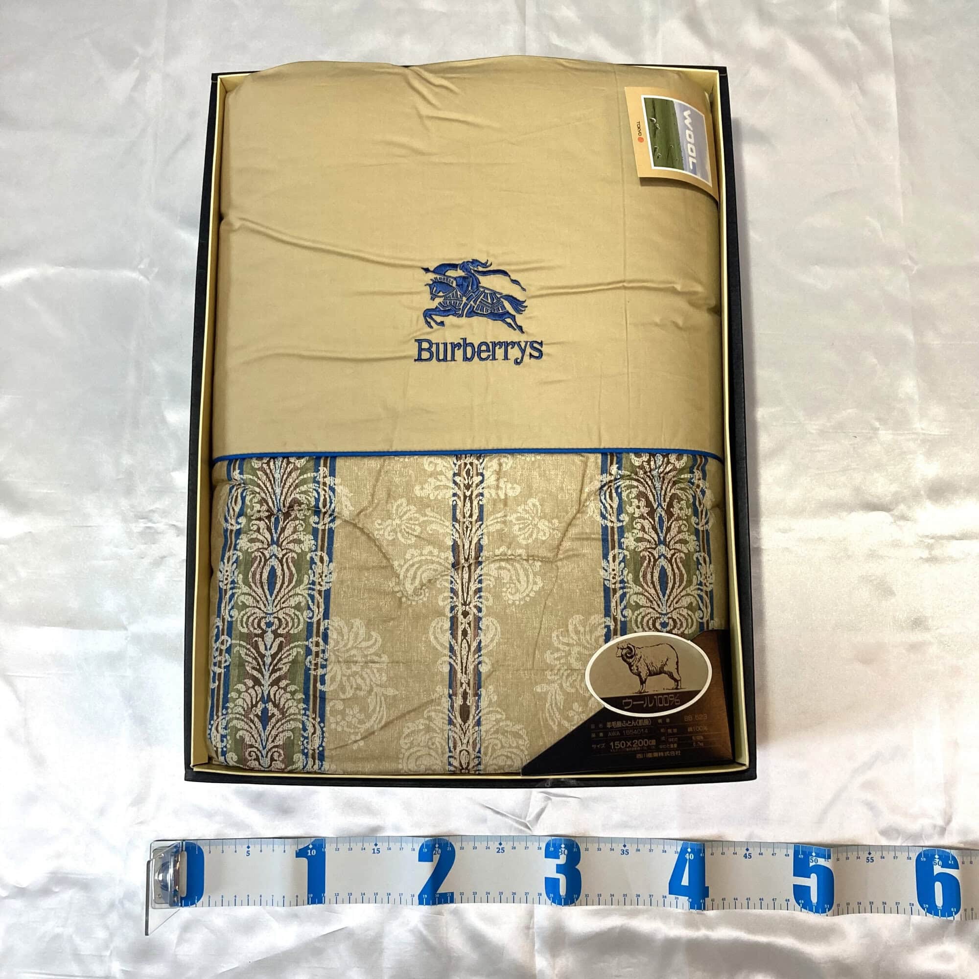 Burberrys quilted comforter in packaging box with measuring tape along the lower edge.