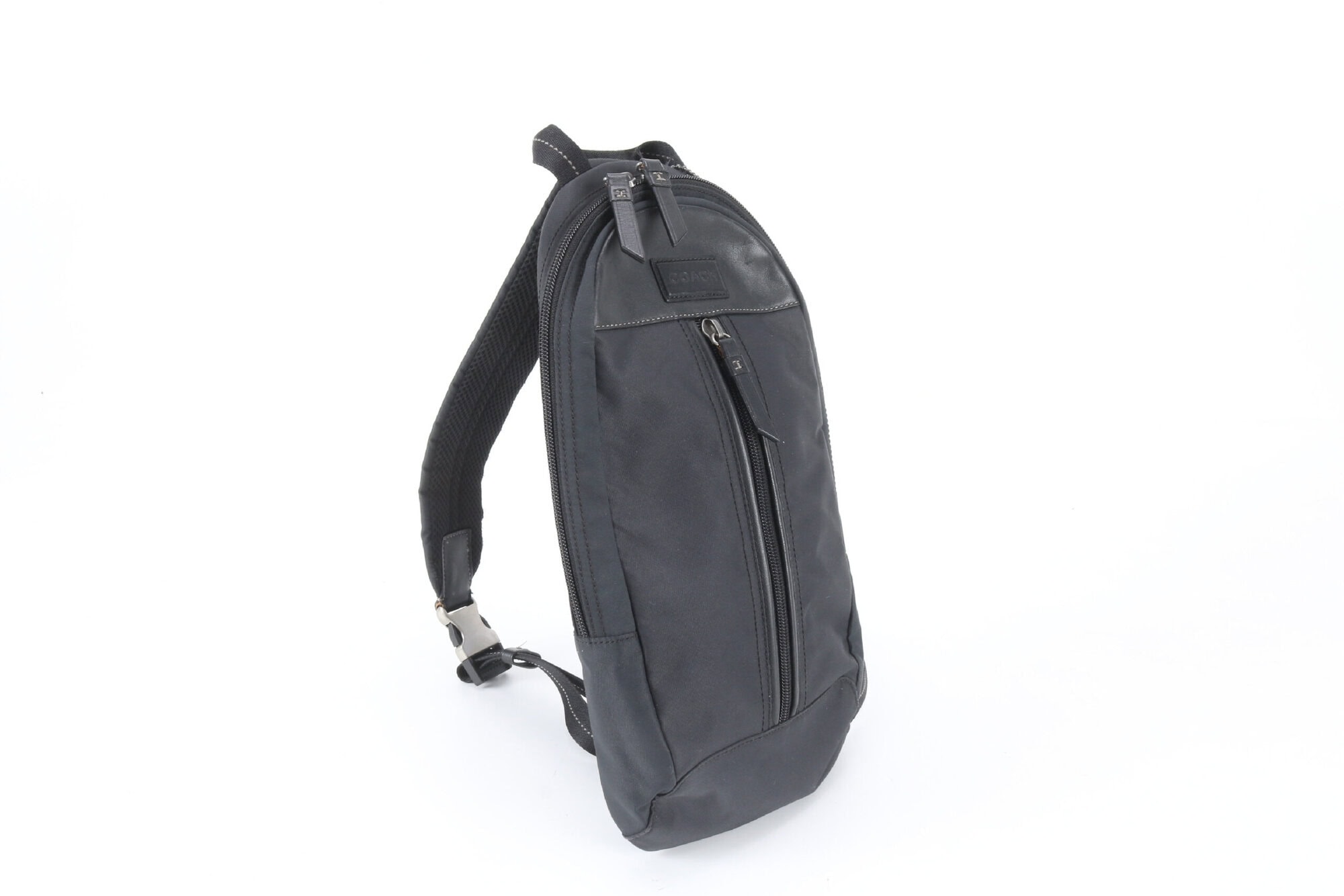 Side profile view of Coach black sling pack showing padded strap