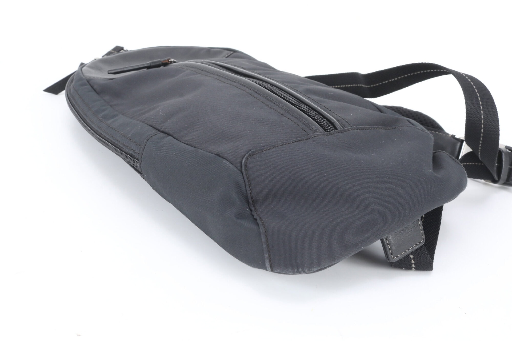 Bottom corner view of Coach black sling pack showing base seam