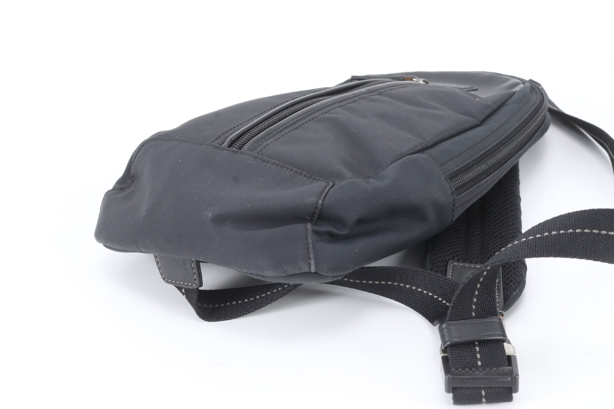 Close-up of opposite base corner on Coach black sling pack