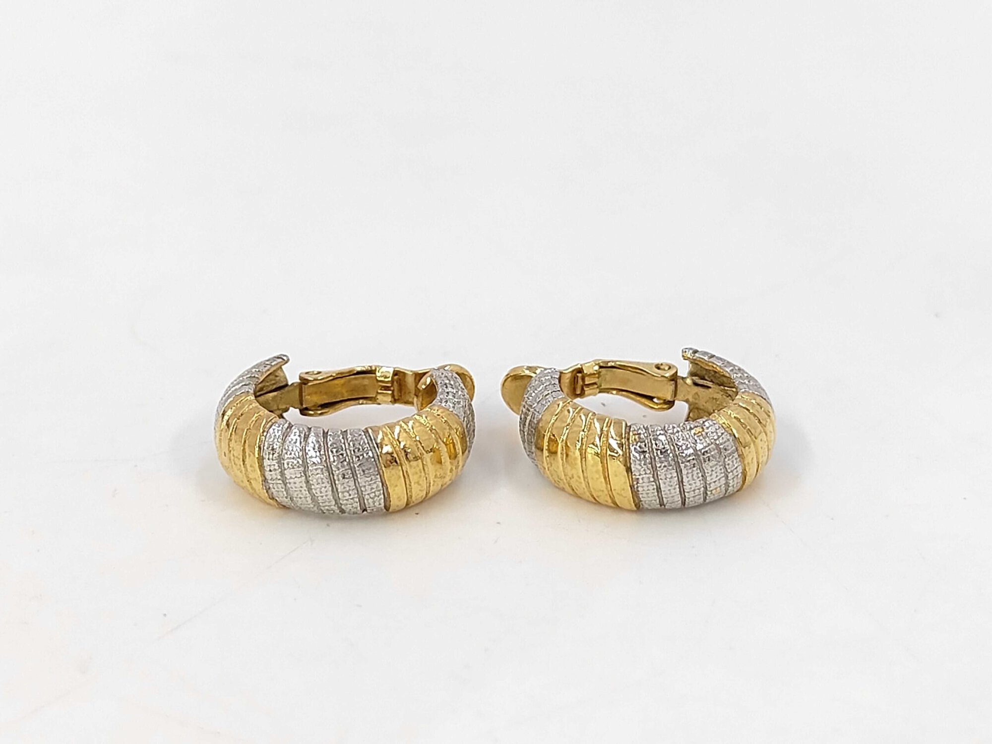 Pair of Givenchy two-tone gold-tone and silver-tone ribbed hoop clip-on earrings standing upright on a white surface.