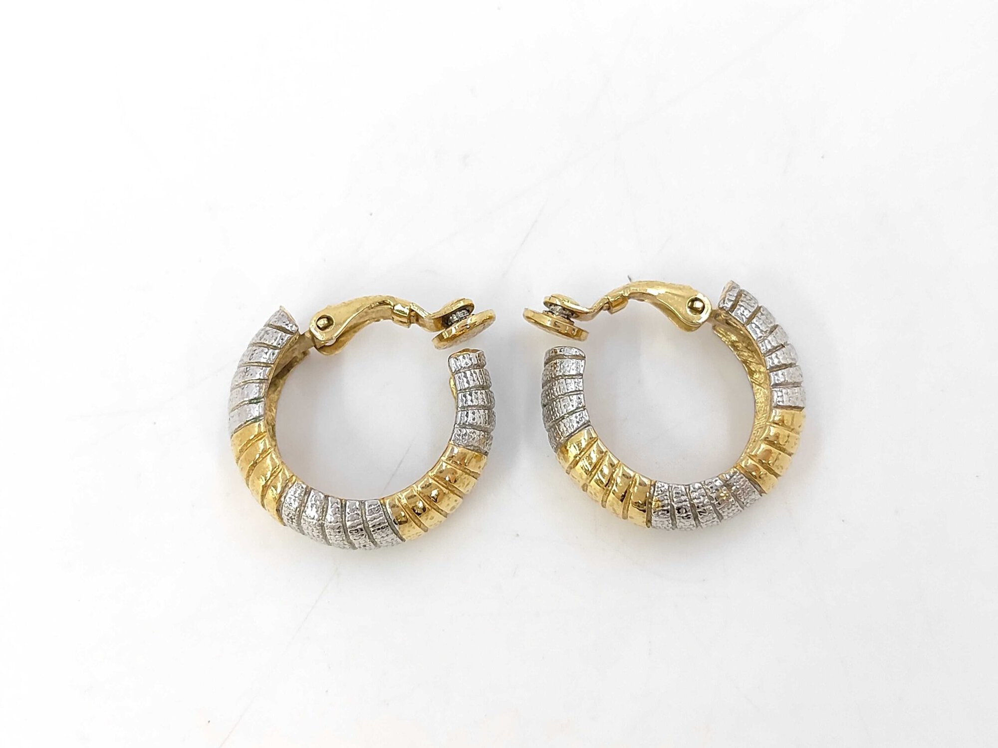 Side profile of Givenchy two-tone ribbed hoop clip-on earrings showing curved half-hoop silhouette and clip hinges.