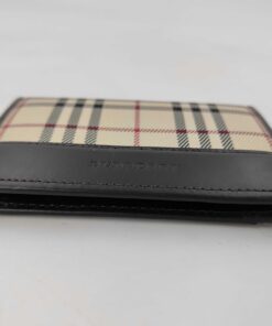 Side view of closed Burberry bifold card case displaying folded edge and stitching.