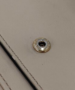 Close-up of gold-tone metal snap closure button engraved with Fendi branding.