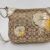 Front view of Coach khaki signature canvas shoulder bag with metallic gold leather trim and multi-layered leather floral appliqués.