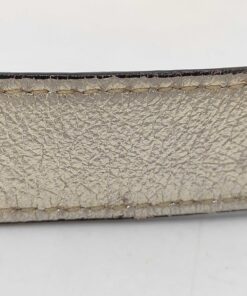 Close-up of metallic gold leather strap surface showing light creasing and edge finish wear.