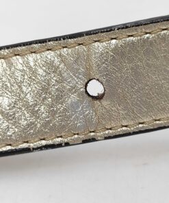 Close-up of adjustment holes on metallic gold leather shoulder strap showing light edge wear.