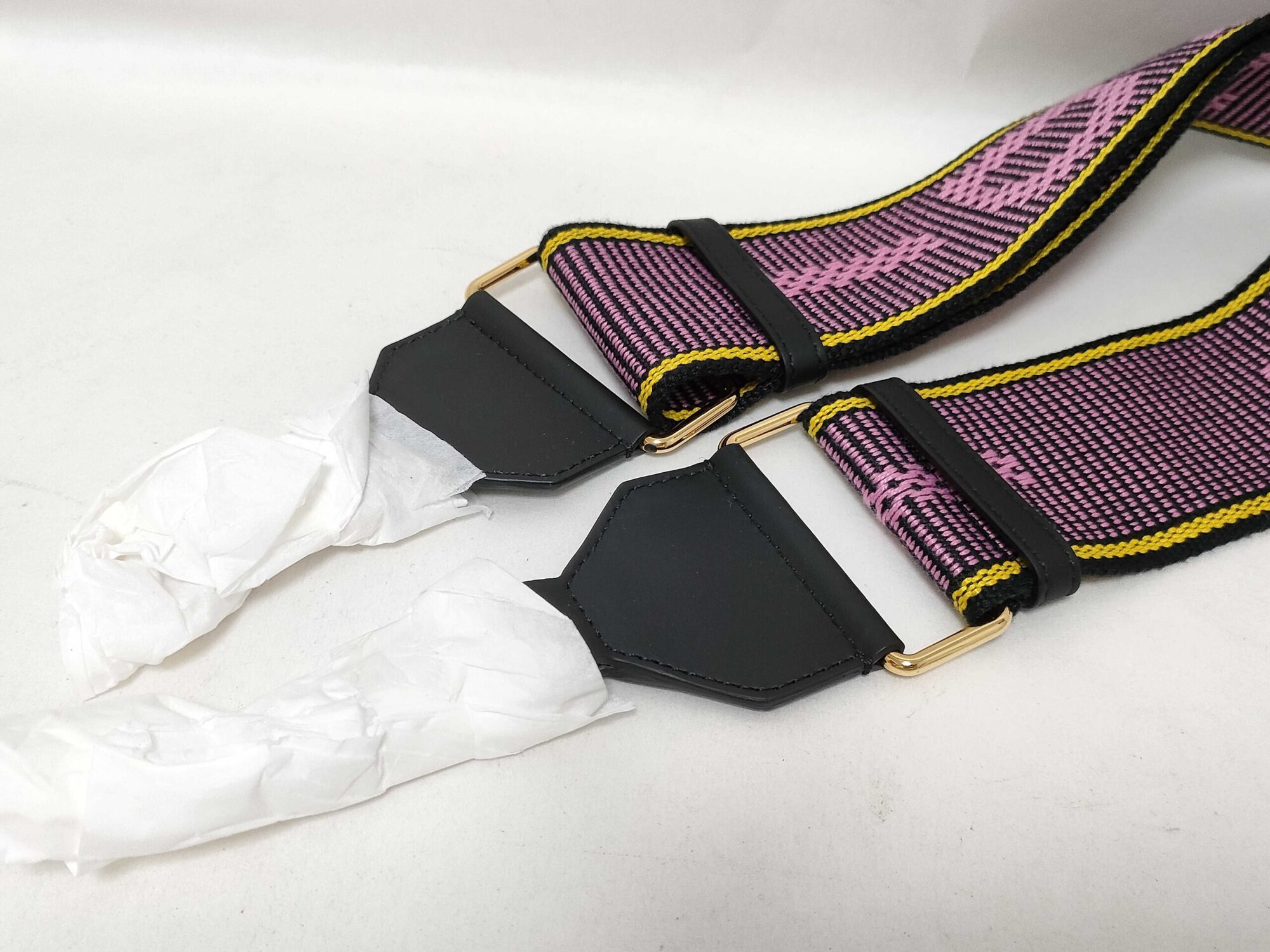 Back angle of black leather end tabs with gold-tone hardware loops and tissue-wrapped clips.