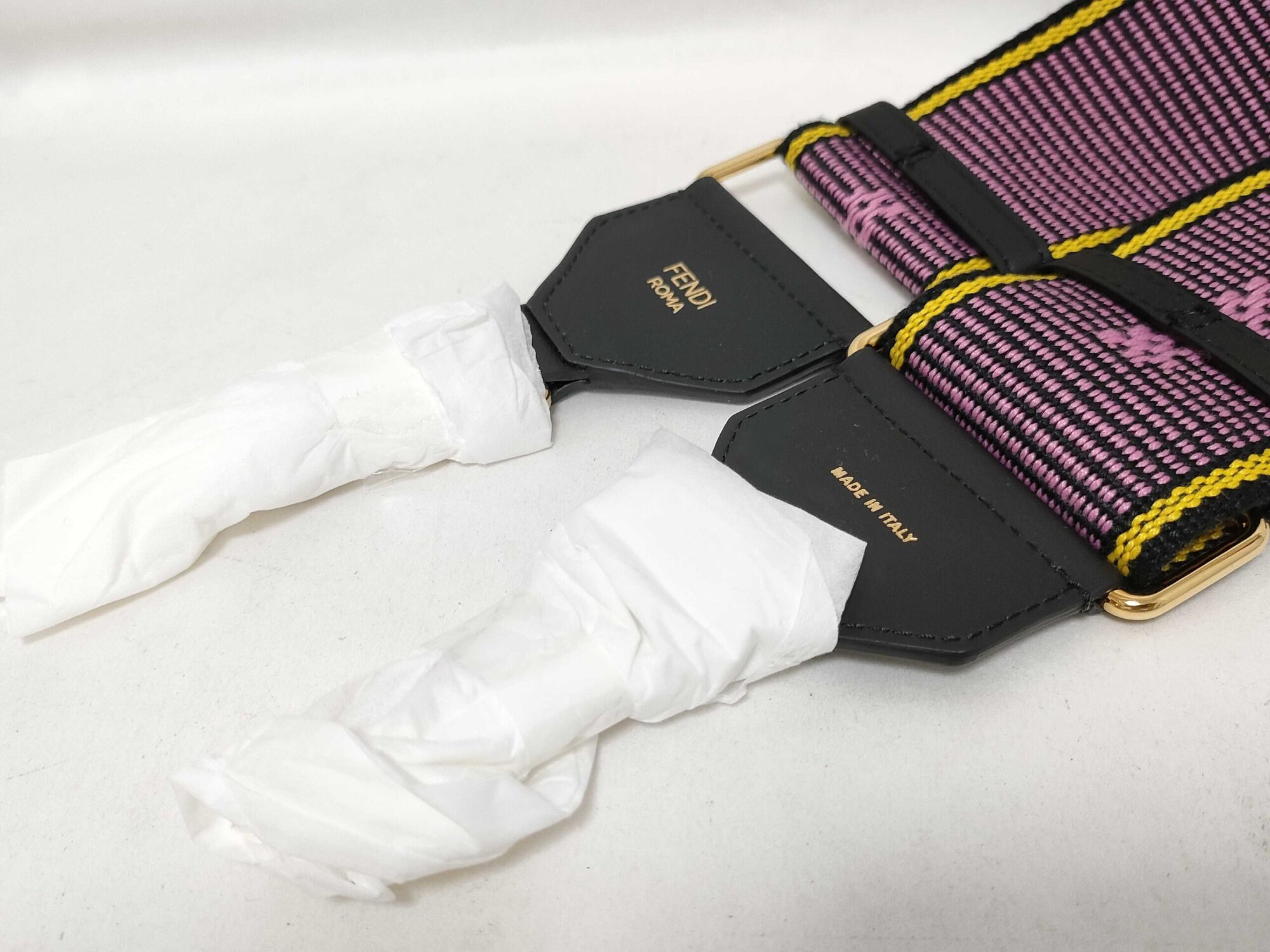Detail of black leather anchor tabs showing FENDI ROMA and MADE IN ITALY gold foil stamping.