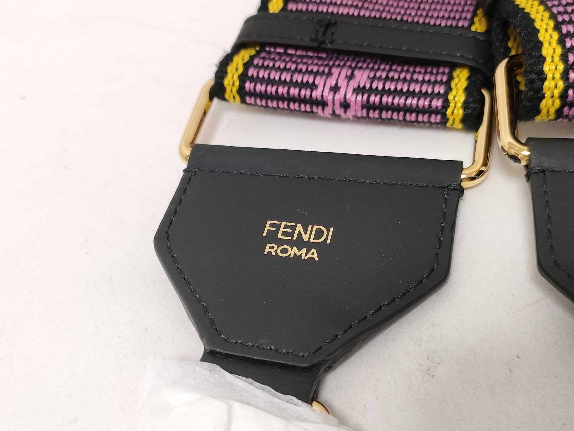 Detail view of black leather end mount displaying gold foil FENDI ROMA signature stamp.