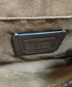 Close-up of stitched leather Coach creed patch on interior pocket wall