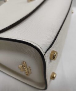 Side gusset and corner view of Coach satchel showing edge glazing and gold-tone base studs