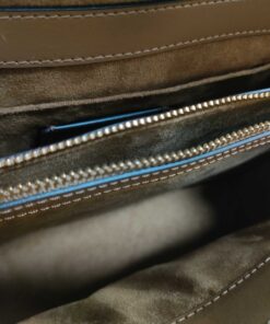 Interior compartment of Coach satchel showing tan textile lining and gold-tone zip wall pocket