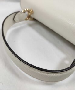 Close-up of rolled leather top handle and gold-tone anchor hardware on Coach satchel