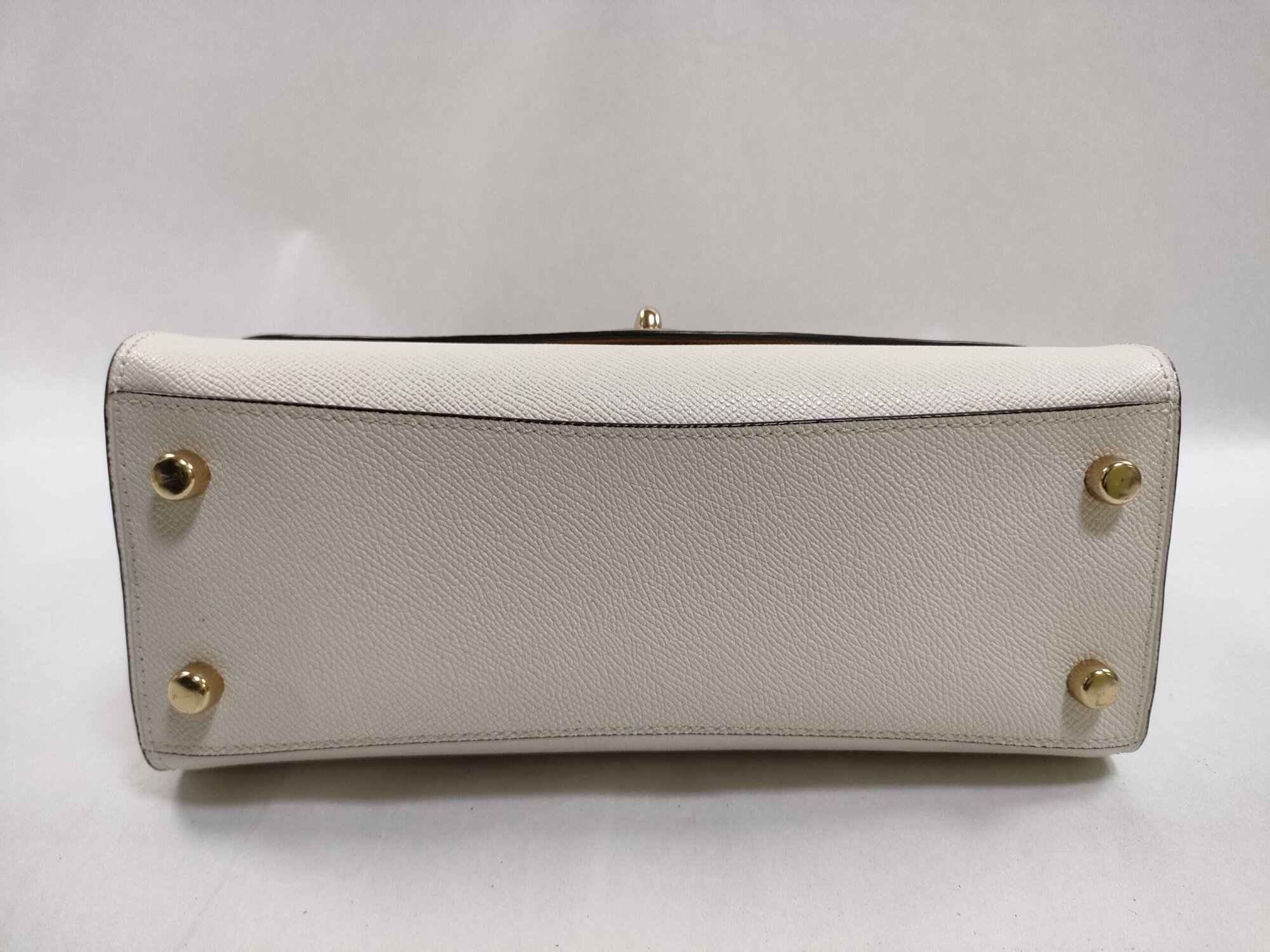 Bottom base of Coach satchel in chalk white crossgrain leather with four protective gold-tone feet