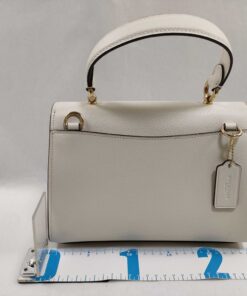 Back view of Coach Tilly satchel showing rear slip pocket, hangtag, D-rings, and measuring tape at base