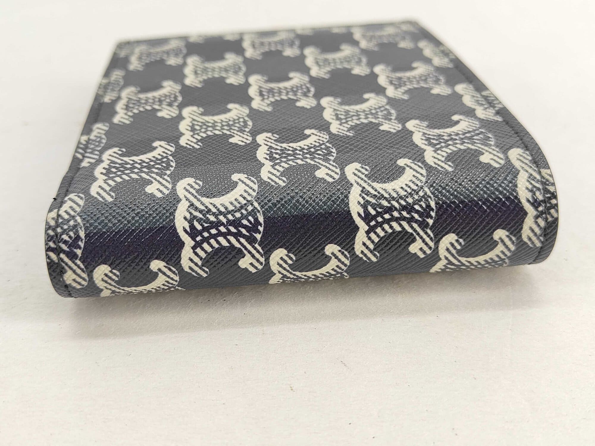 Exterior spine fold of Celine bifold wallet in black Triomphe monogram coated canvas.