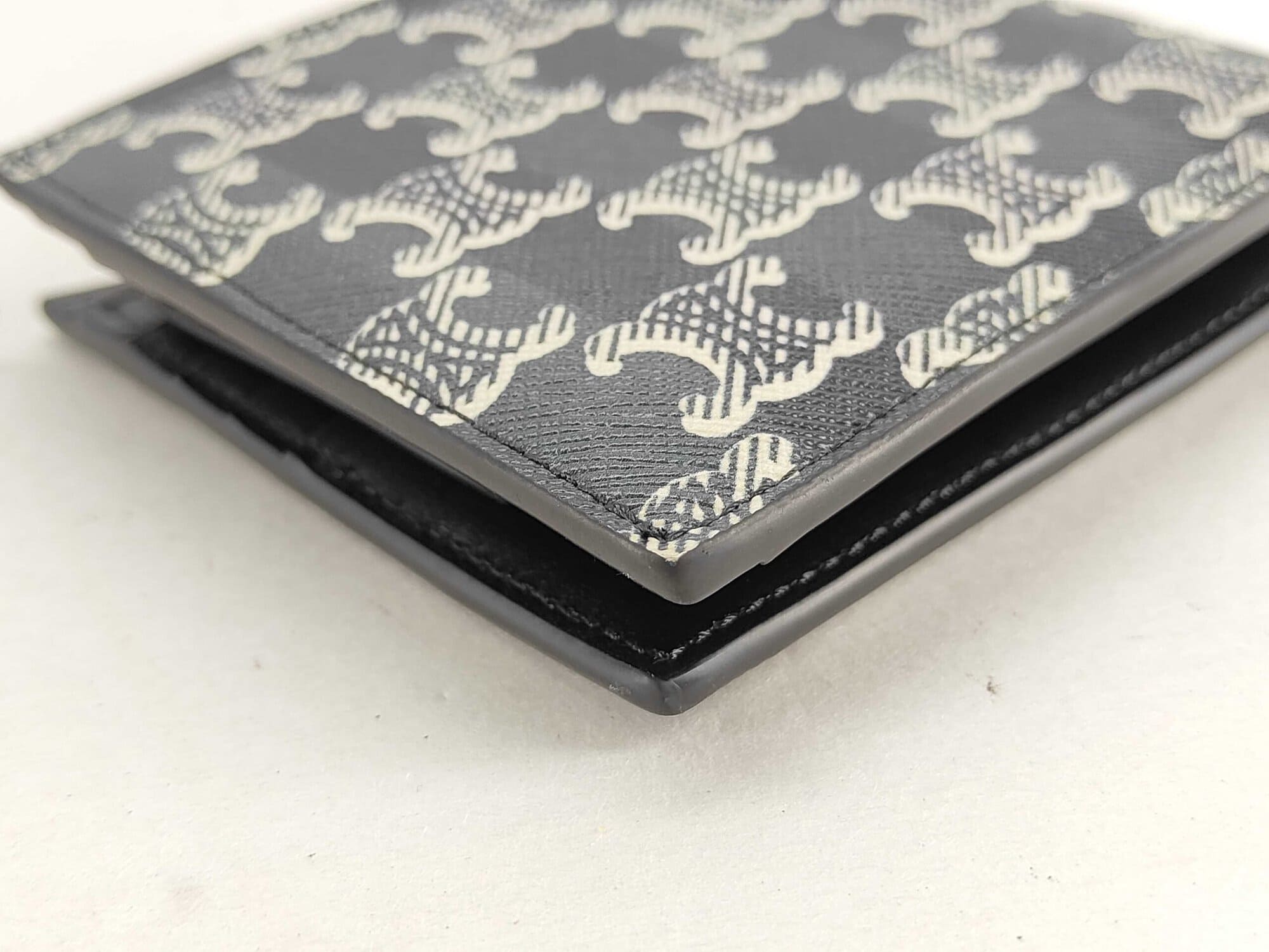 Close-up of exterior corner edge glazing on Celine Triomphe canvas bifold wallet.