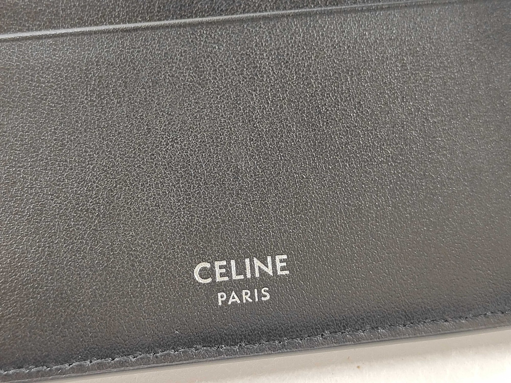Macro view of silver foil Celine Paris logo stamped on black leather interior.