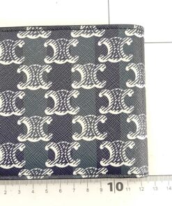 Celine black Triomphe canvas bifold wallet measured flat against a metric grid ruler.