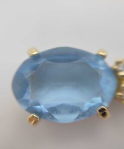 Macro view of the faceted oval light-blue stone held by gold-tone prongs on Christian Dior necklace.