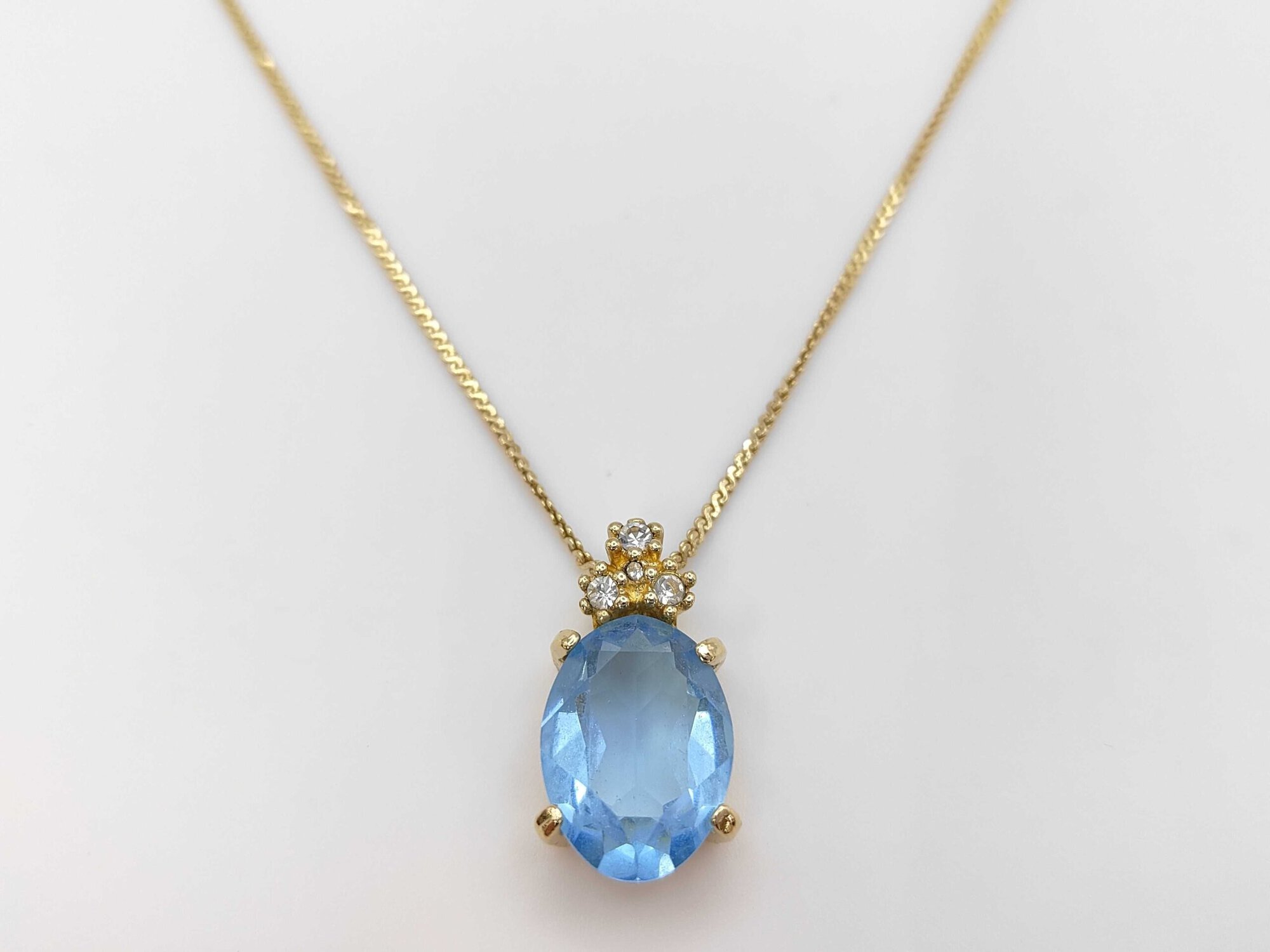Christian Dior gold-tone pendant necklace featuring an oval light-blue faceted stone crowned with clear accent stones.