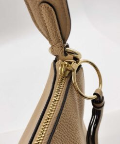 Close-up of gold-tone zipper slider with ring attachment and leather tassel pull