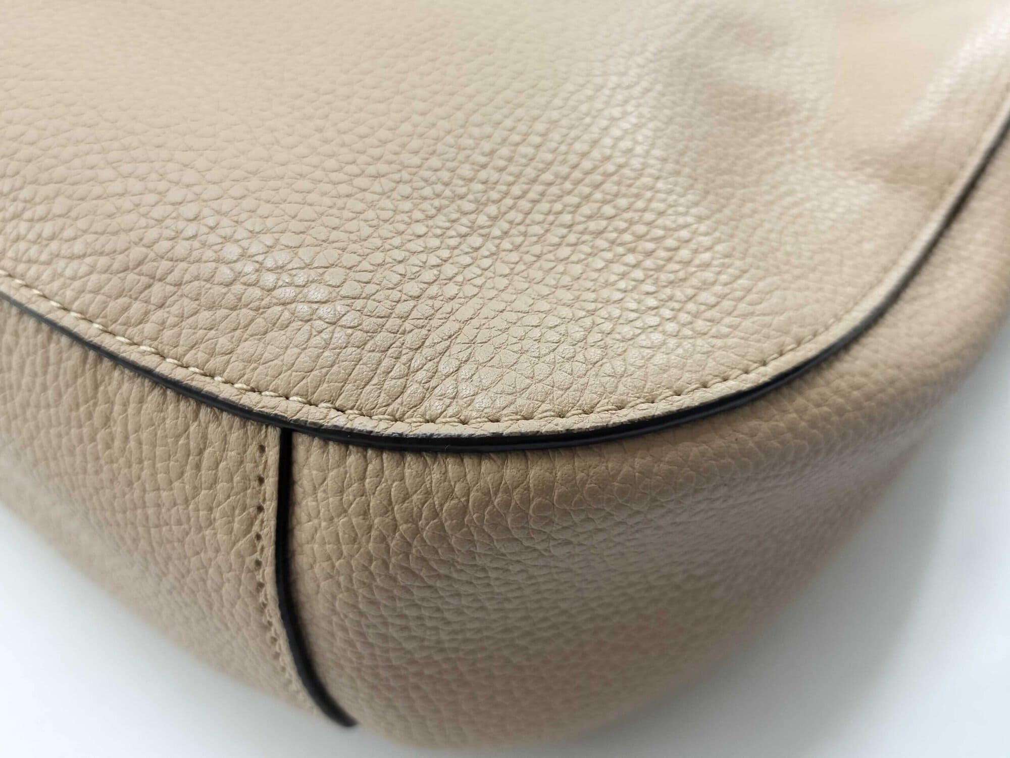 Close-up of base corner on pale gold pebble leather showing minimal contact wear