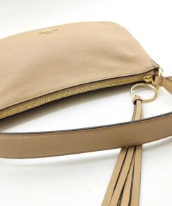 Top-down view of Coach Sutton bag showing zipper closure, handle, and tassel pull