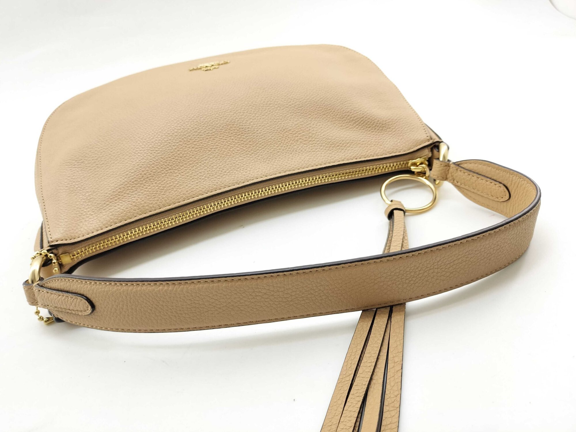 Top-down view of Coach Sutton bag showing zipper closure, handle, and tassel pull