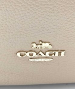 Close-up of gold-tone Coach Horse and Carriage metal logo on pebble leather