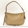 Front view of Coach Sutton pale gold metallic pebble leather shoulder bag resting on dust bag