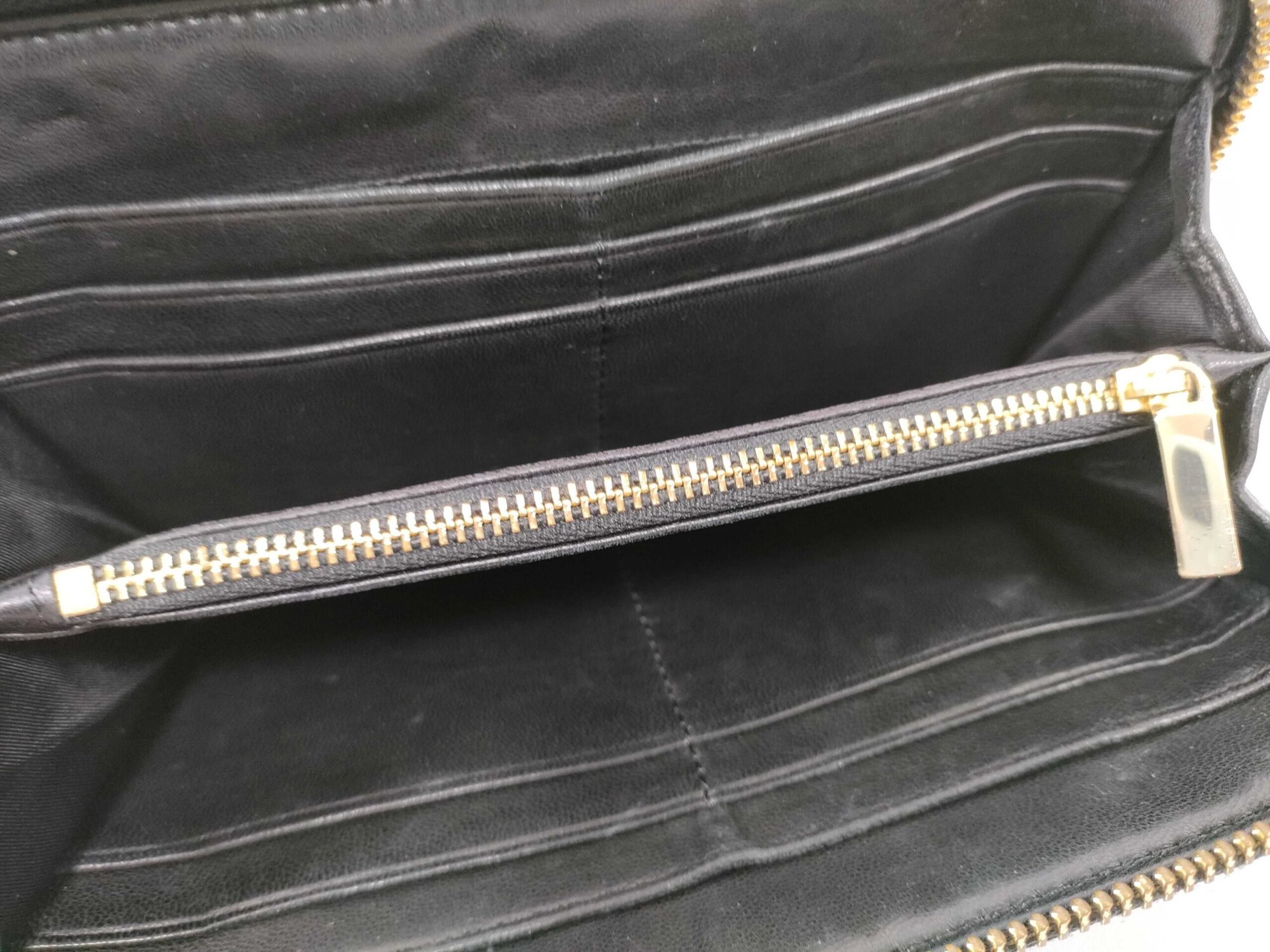 Fully opened interior of black leather Tory Burch wallet showing eight card slots and center zip compartment.