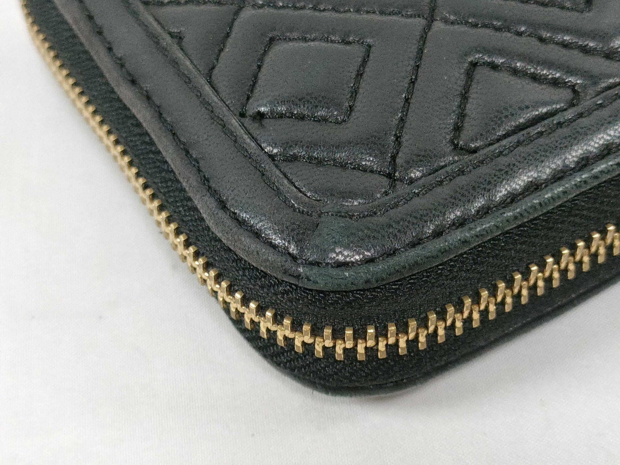 Close-up of bottom corner on black quilted leather Tory Burch wallet showing light edge wear.