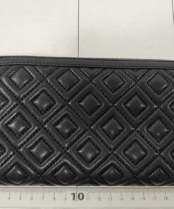Back quilted panel of black Tory Burch Fleming continental wallet laid against a grid ruler.
