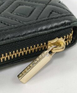 Close-up of gold-tone metal zipper pull engraved with Tory Burch logo lettering.