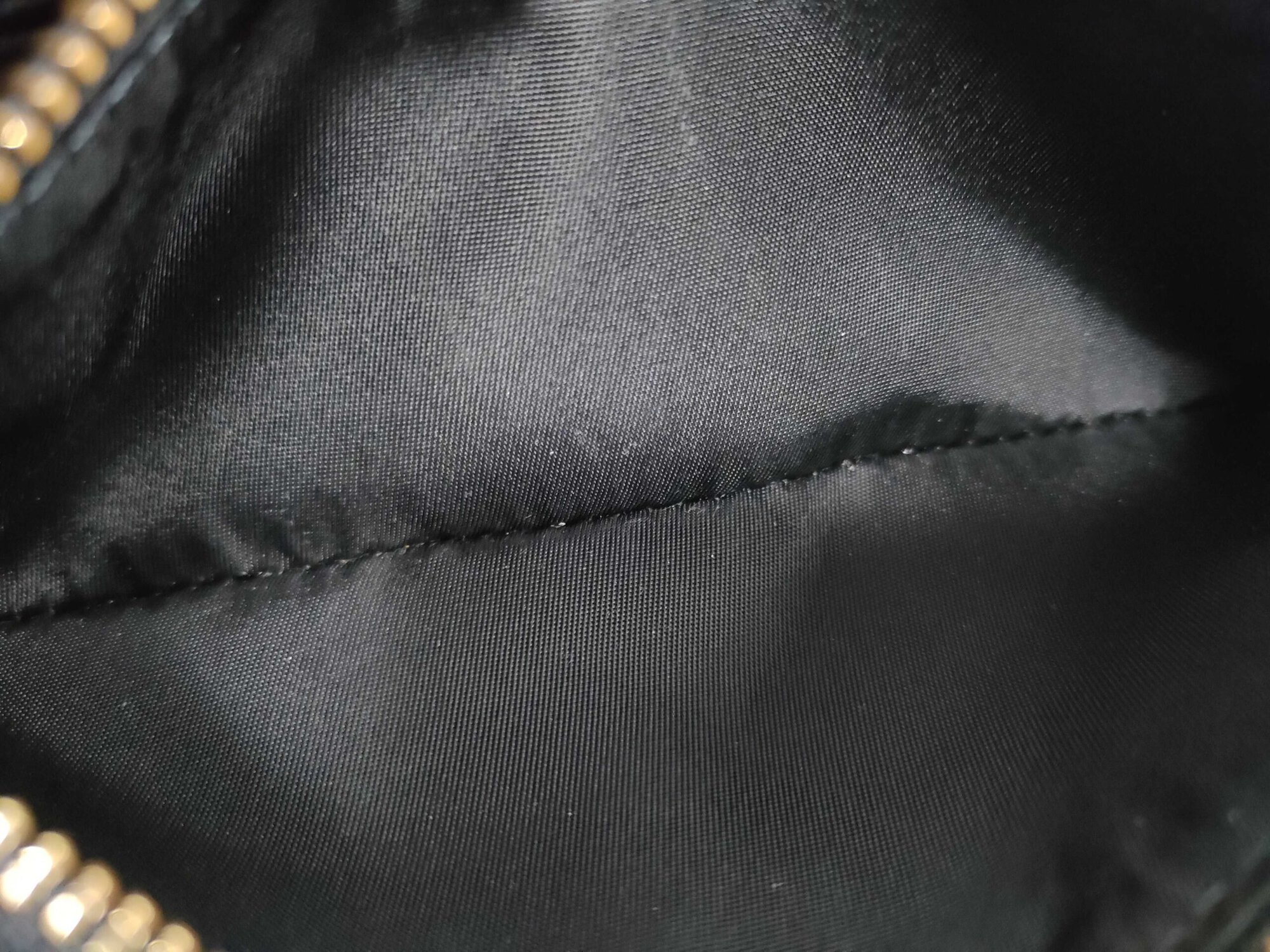 Interior view of black fabric lining inside central zippered coin pocket.