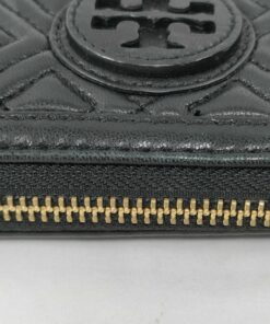 Detailed view of exterior stitched edge trim and gold-tone zipper teeth on black leather wallet.