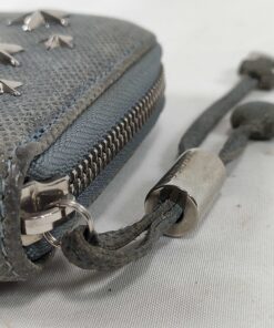 Close-up of knotted leather zipper pull with engraved Jimmy Choo metal cylinder slider.