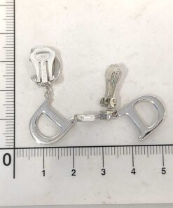 Christian Dior CD logo drop clip-on earrings positioned beside a metric centimeter ruler.