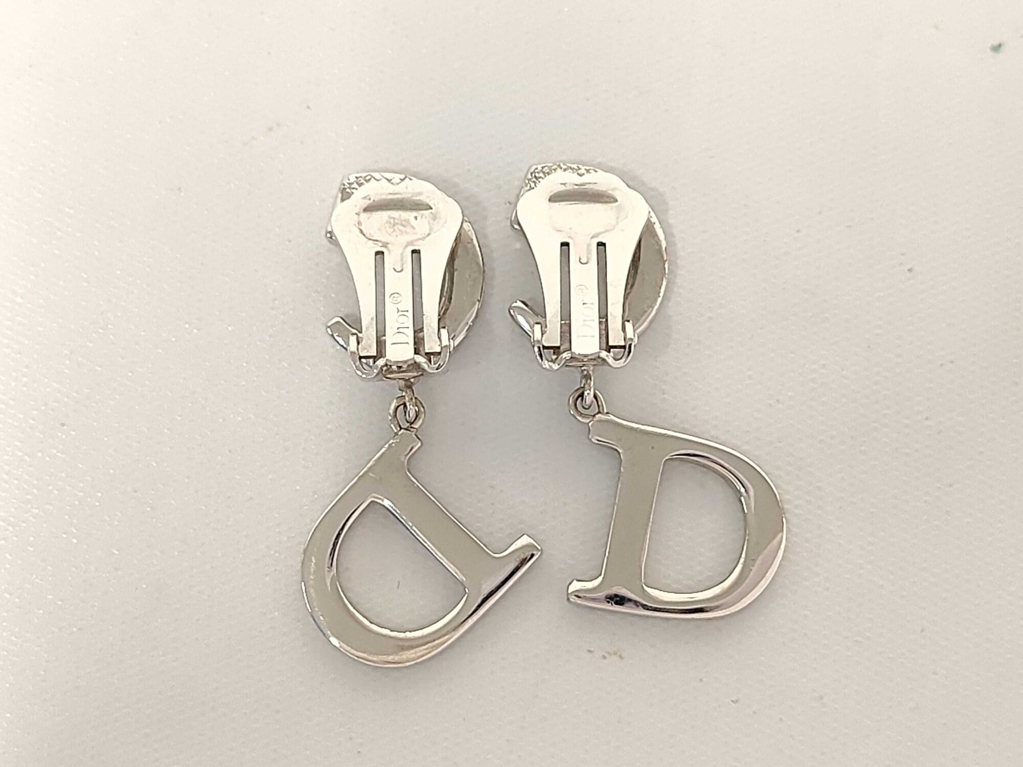 Back view of Christian Dior CD logo drop earrings displaying closed paddle clip-on backings.