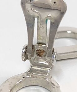 Macro view of earring clip-on hinge showing spring mechanism and localized tarnish.