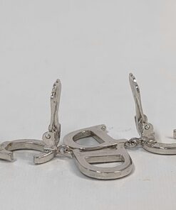 Side angle view of Christian Dior CD logo drop earrings resting with paddle clips upright.