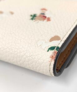 Close-up of lower corner edge showing slight rubbing on Coach floral key case.