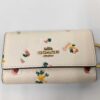 Front view of Coach chalk pebble leather floral 6-ring key case with gold-tone logo.