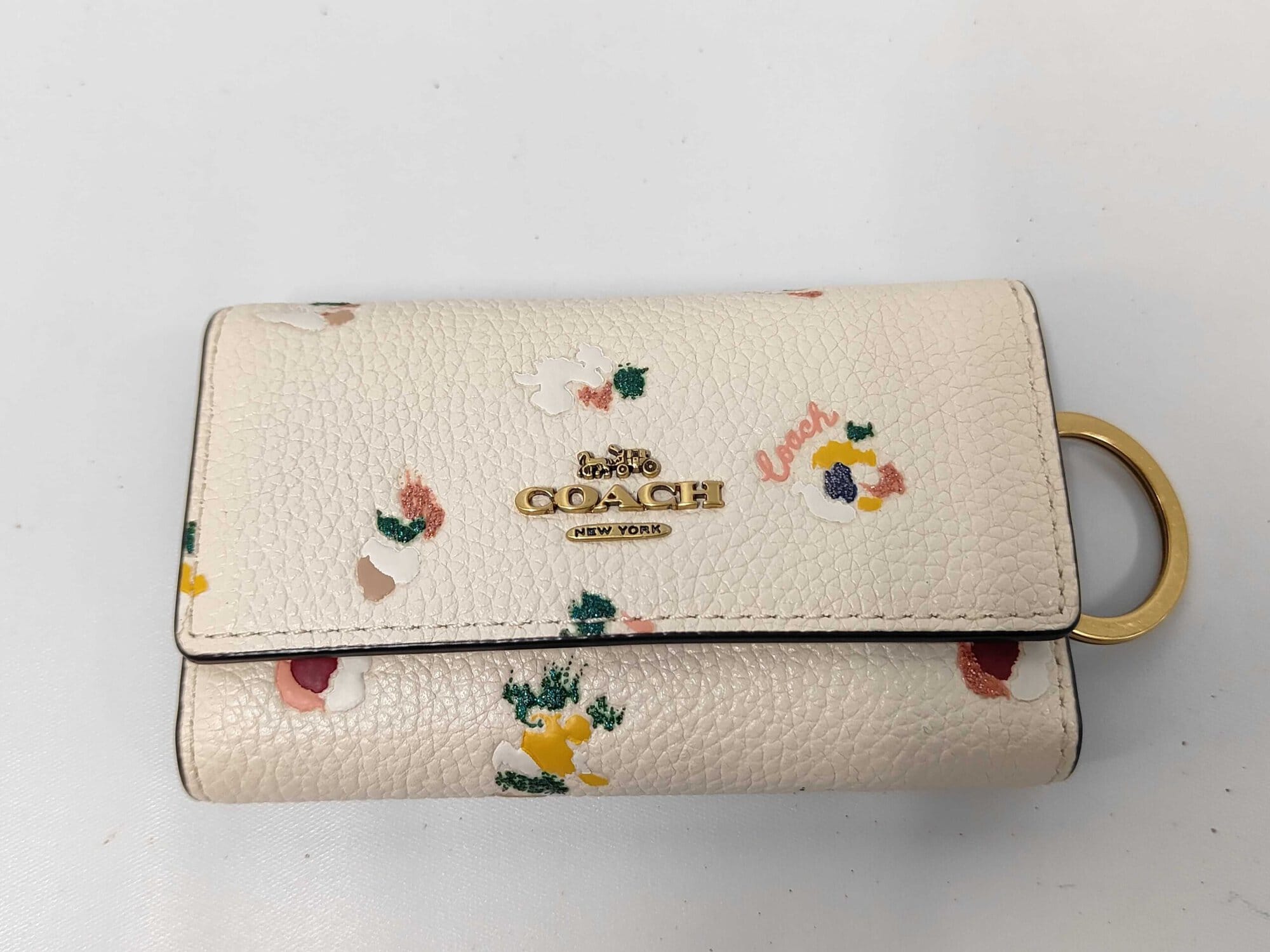 Front view of Coach chalk pebble leather floral 6-ring key case with gold-tone logo.
