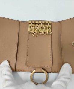Open interior view of Coach key case showing tan leather, six key hooks, and key ring.